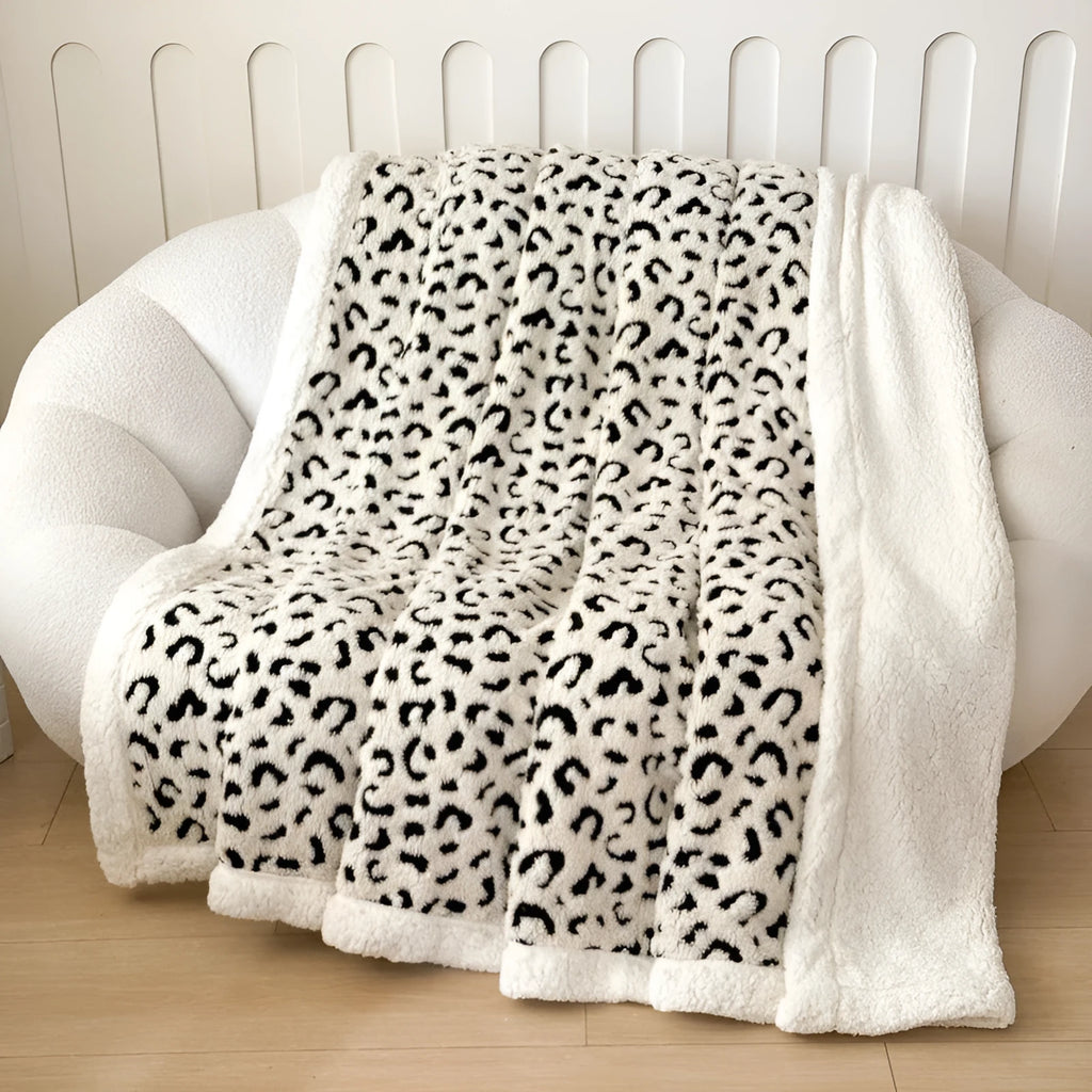 Double-layer jacquard taffeta blanket with leopard print pattern in camel colour on a bed.