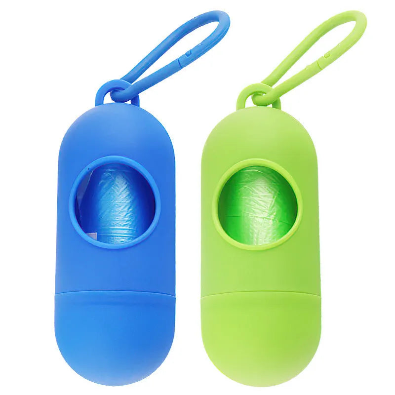 Compact black dog poop bag dispenser with side hook and Velcro strap, shown next to a roll of waste bags.