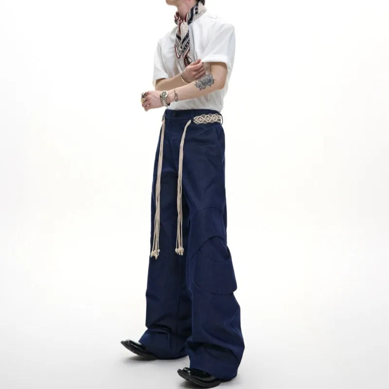 Man wearing dark blue straight leg jeans with belt stitching and decorative details