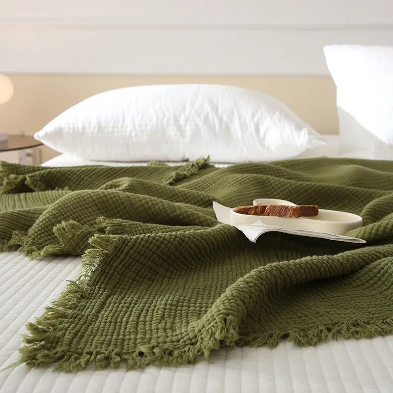 Four-layer gauze cotton blanket with tassel trim in navy blue colour laid flat.