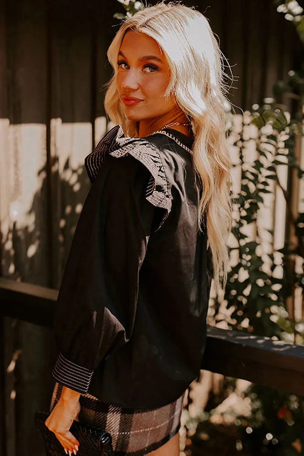 Black V-neck blouse with contrast stitching and ruffle long sleeves on hanger
