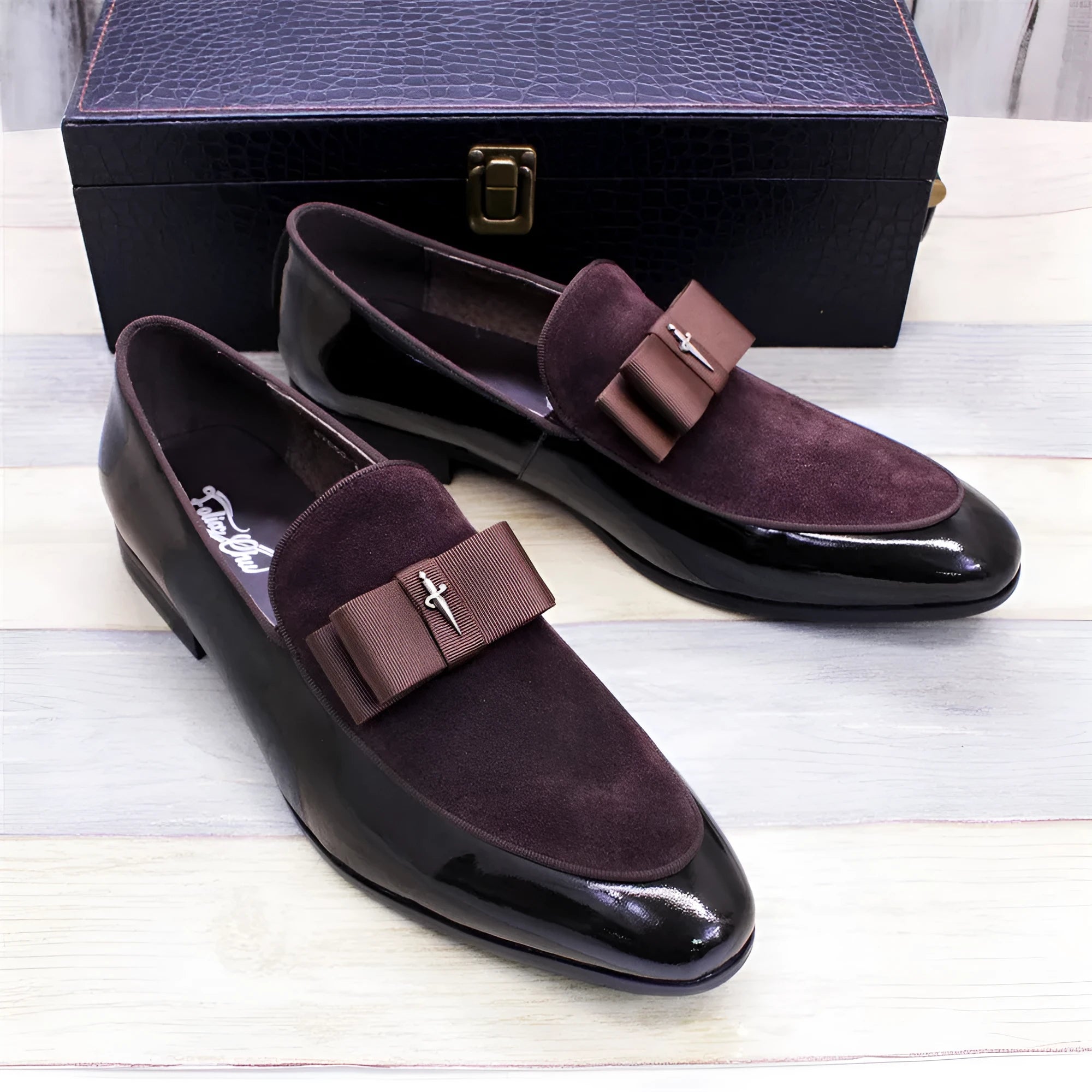 Men's glossy black patent leather low-top shoes with a tassel detail on a rubber sole.