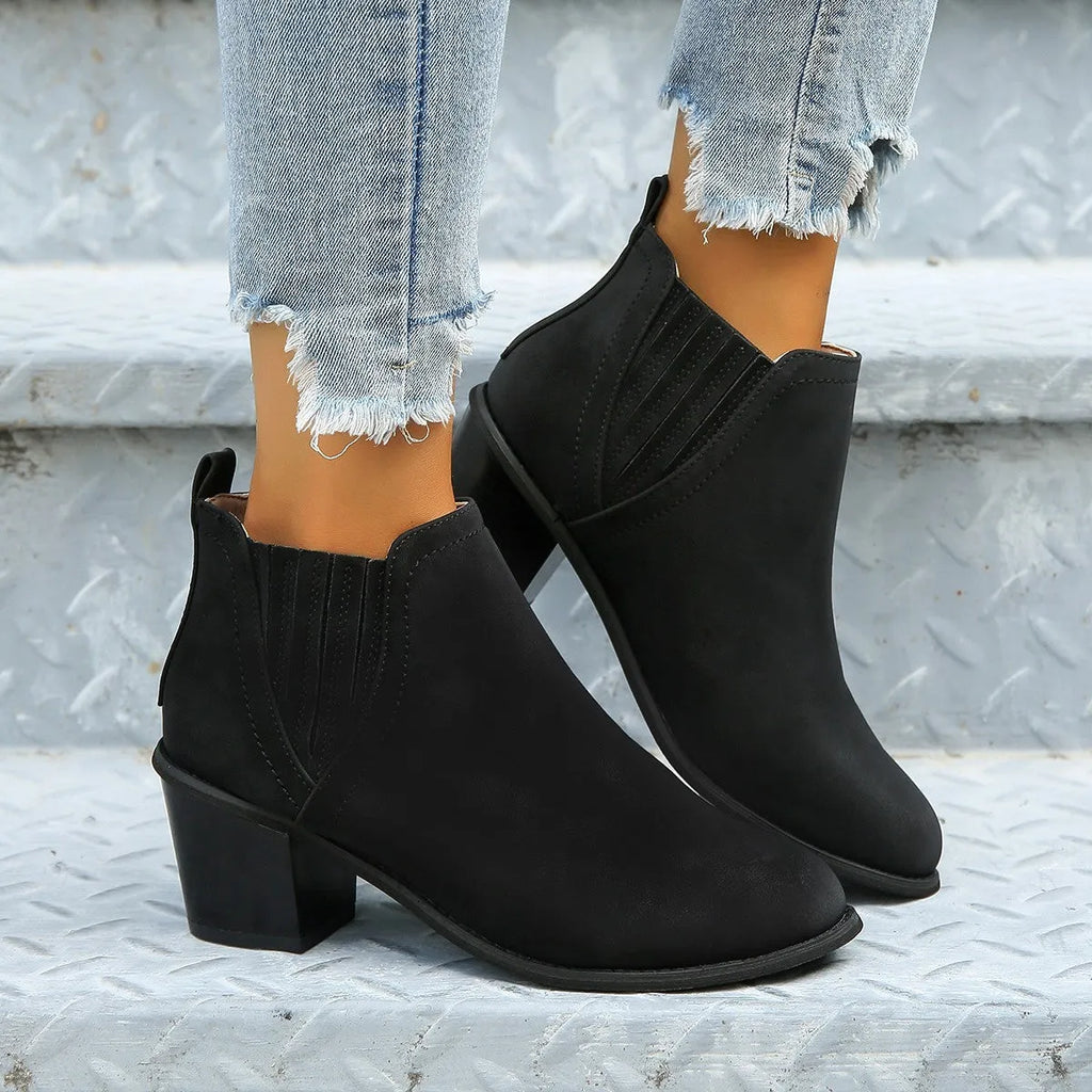 Women's black pointed toe ankle boots with a thick square low heel and slip-on design.