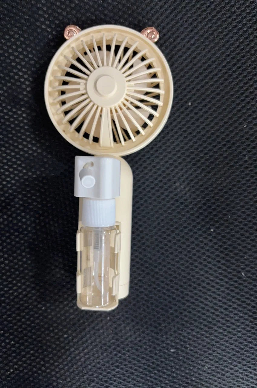 Compact plastic USB desktop fan with nozzle, shown in apricot colour, beside a USB cable on a desk.
