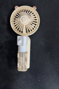 Compact plastic USB desktop fan with nozzle, shown in apricot colour, beside a USB cable on a desk.