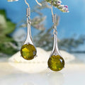 Olive green topaz coloured drop-shaped retro earrings for women on a plain background.