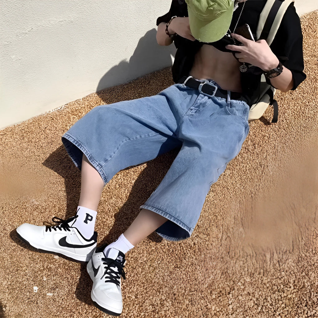 Man wearing blue high-waist straight-leg denim pirate shorts, showing cropped length and zipper fly