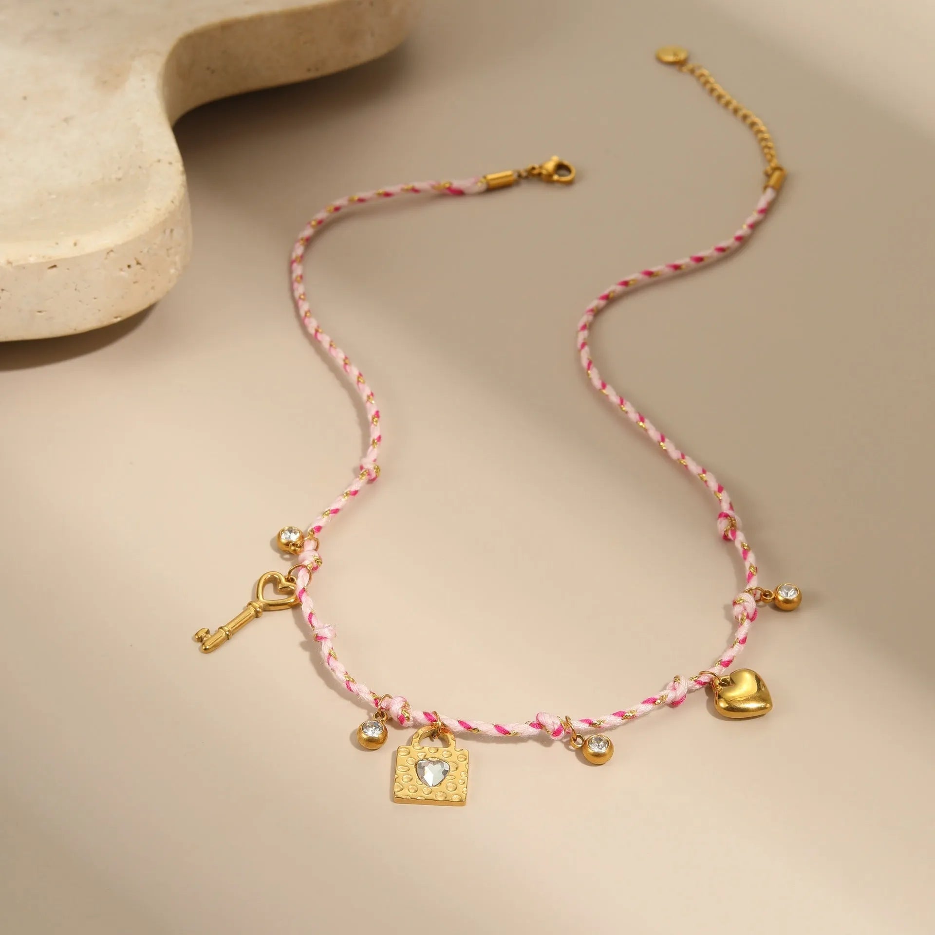 Close-up of a women's braided rope and titanium steel design necklace with a heart-shaped pendant on a stainless steel chain.
