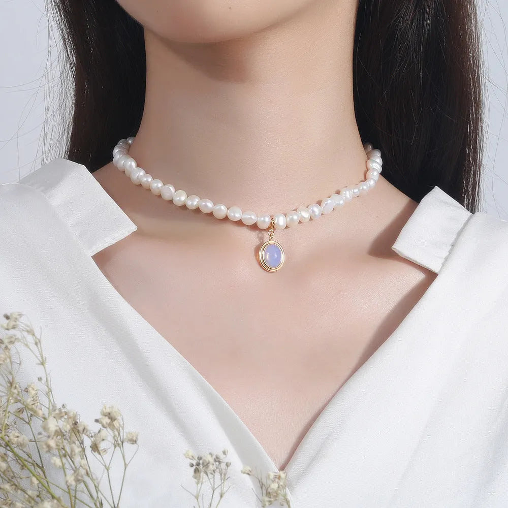 Round medal pearl necklace with geometric silver pendant and irregular pearls on a silver chain.