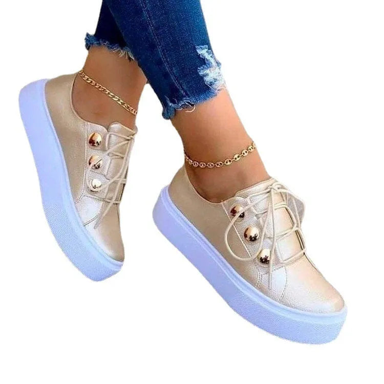 Women's lace-up flats sneakers with rivet detailing in gold colour showing round toe and front tie closure