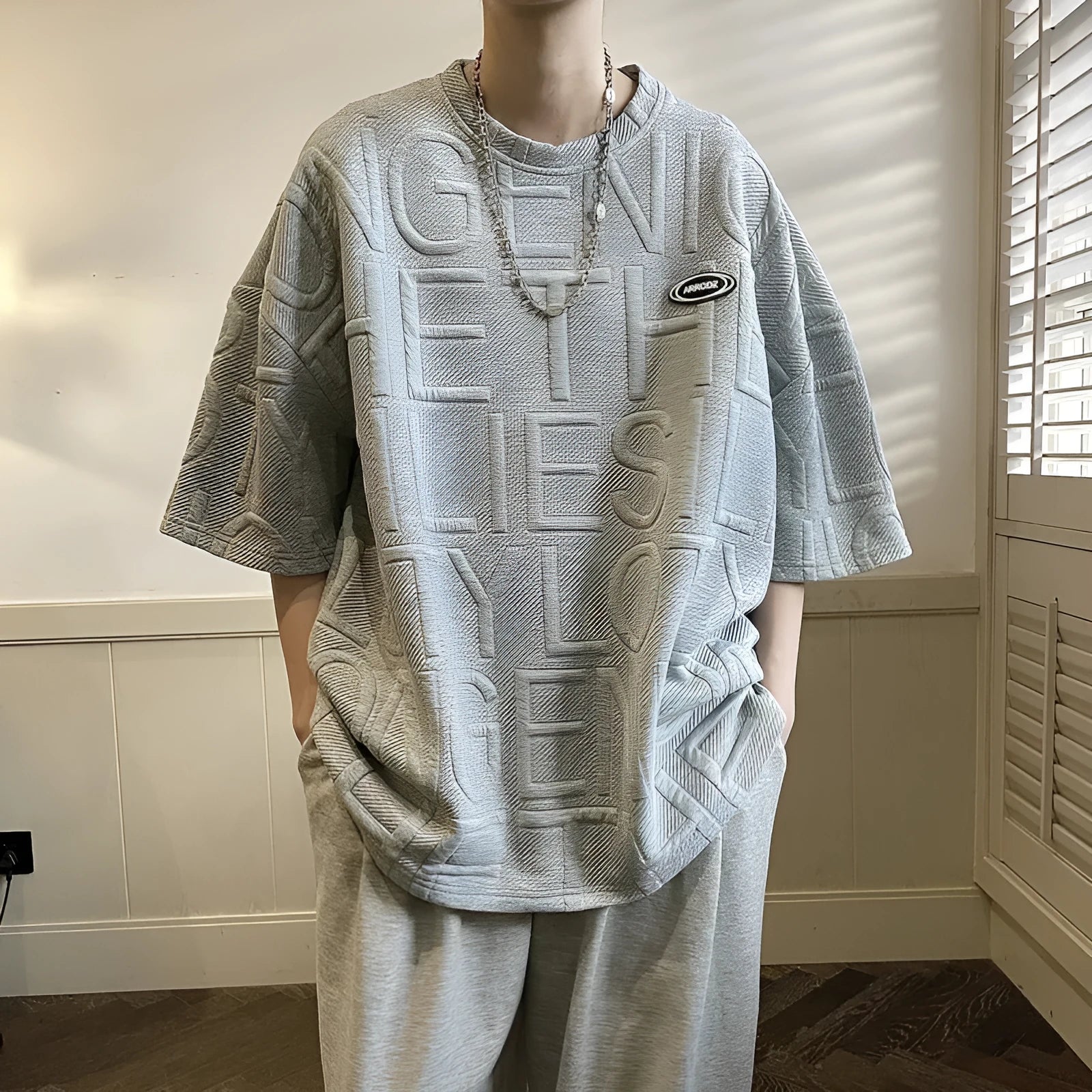Men's grey loose fit T-shirt with a three-dimensional retro letter pattern on the front.