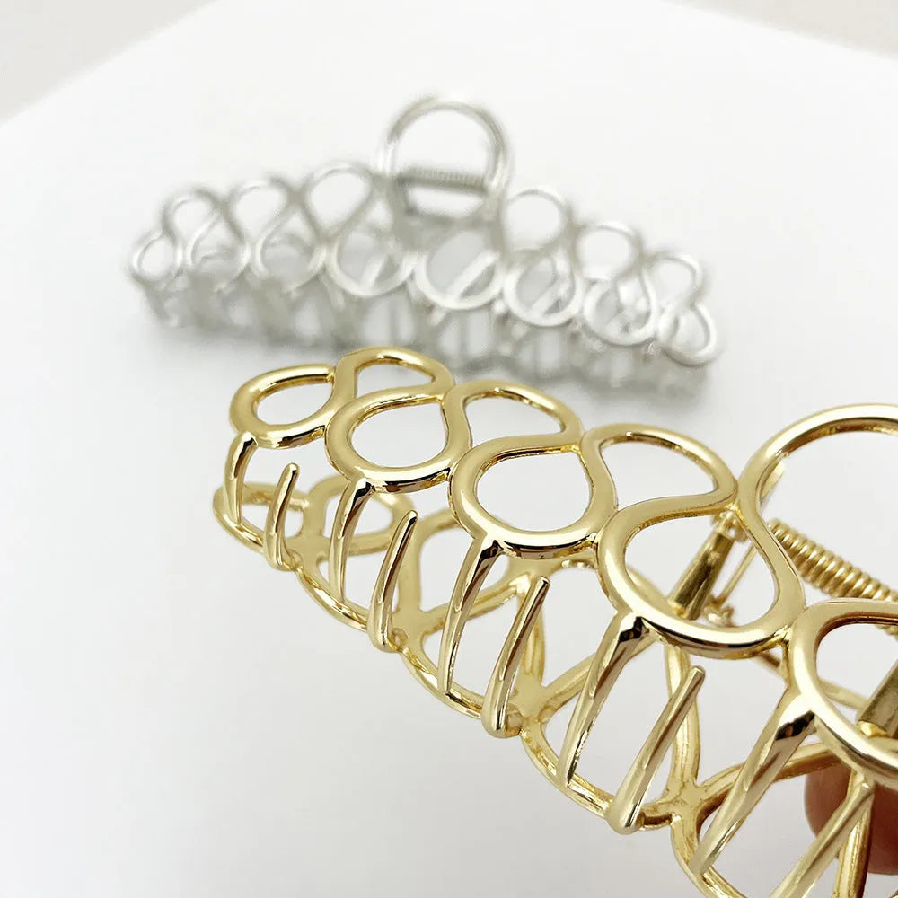 Large minimalist hair clip with tassel decoration in gold finish showing irregular shape design
