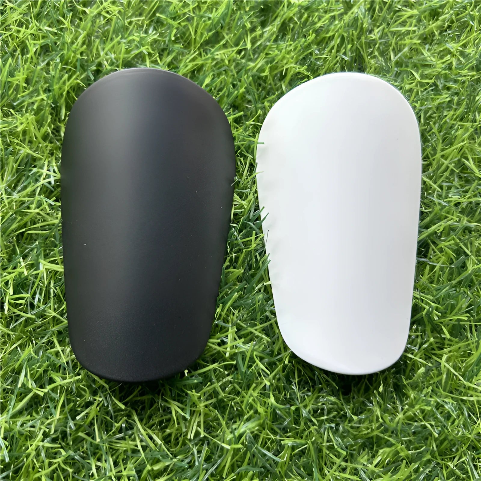 Extra small plastic football shin guards measuring 8x5cm in black and white for youth players