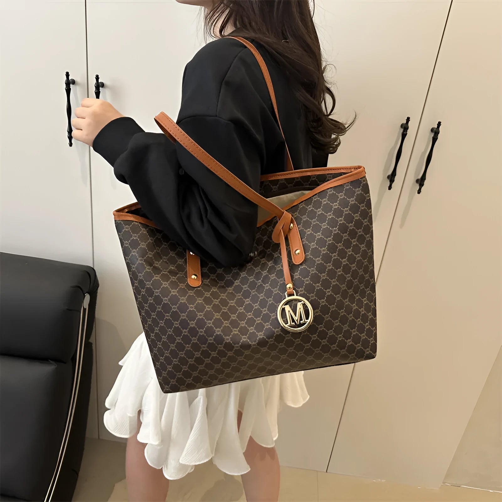 Women's black PU leather shoulder bag with sewing thread detail on a table.