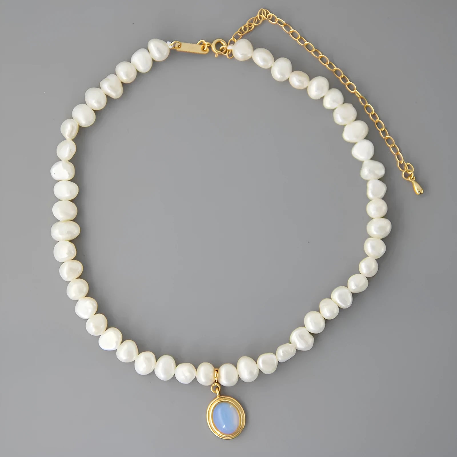 Round medal pearl necklace with geometric silver pendant and irregular pearls on a silver chain.