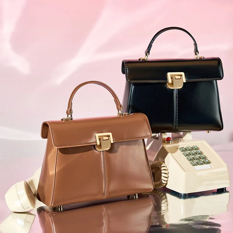 Black genuine leather women's shoulder bag with clasp closure showing square shape and adjustable strap