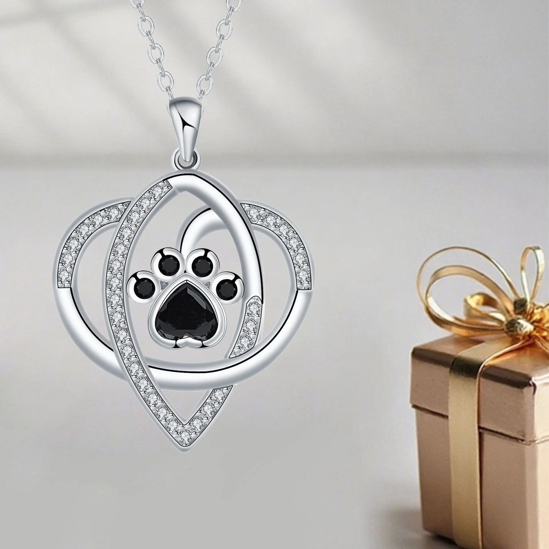 Close-up of a copper pendant necklace showing a charm with dog paw and cat footprint designs on a cross chain.