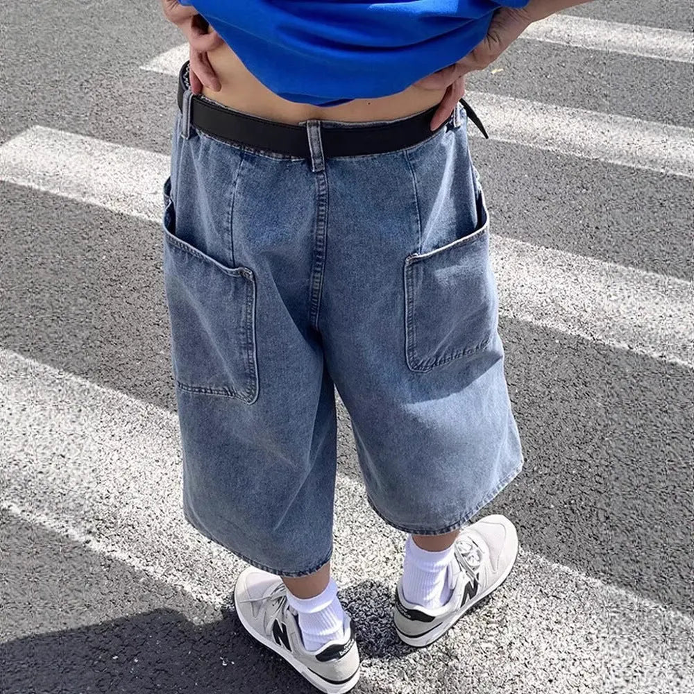 Man wearing blue high-waist straight-leg denim pirate shorts, showing cropped length and zipper fly