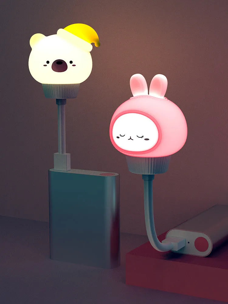 White cartoon bear-shaped USB night light with remote control on a wooden table.