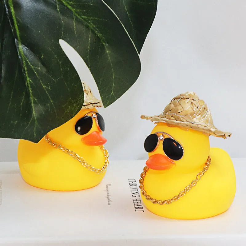 Cartoon yellow duck wearing a straw hat car dashboard ornament on a matte yellow base.