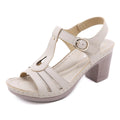 Women's patent leather sandals with thick high heel, metal buckle, and stitching detail in apricot colour.