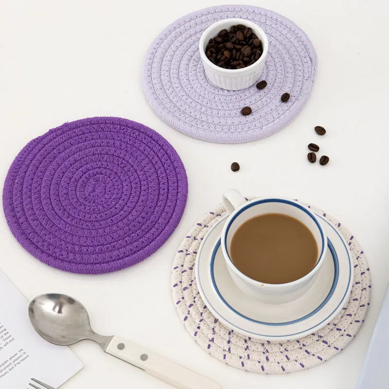 Set of three round grey cotton cord coasters on a wooden table