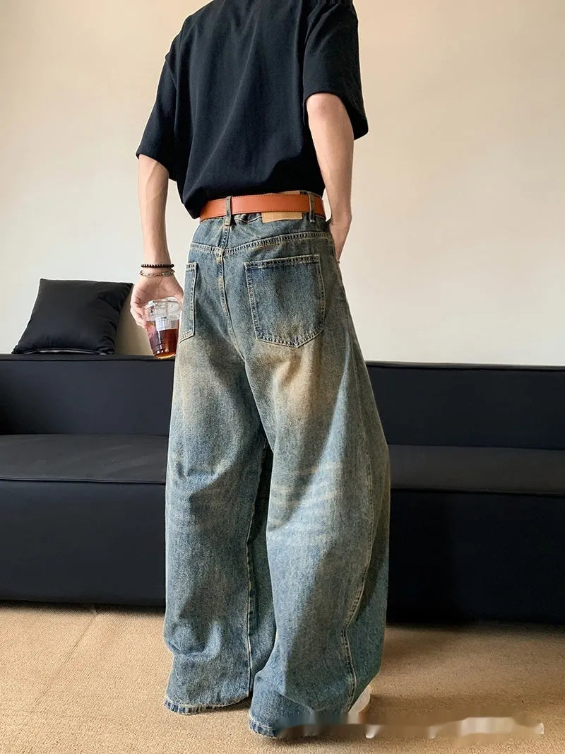 Man wearing retro blue distressed wide-leg denim jeans with a slimming fit and mid waist design.