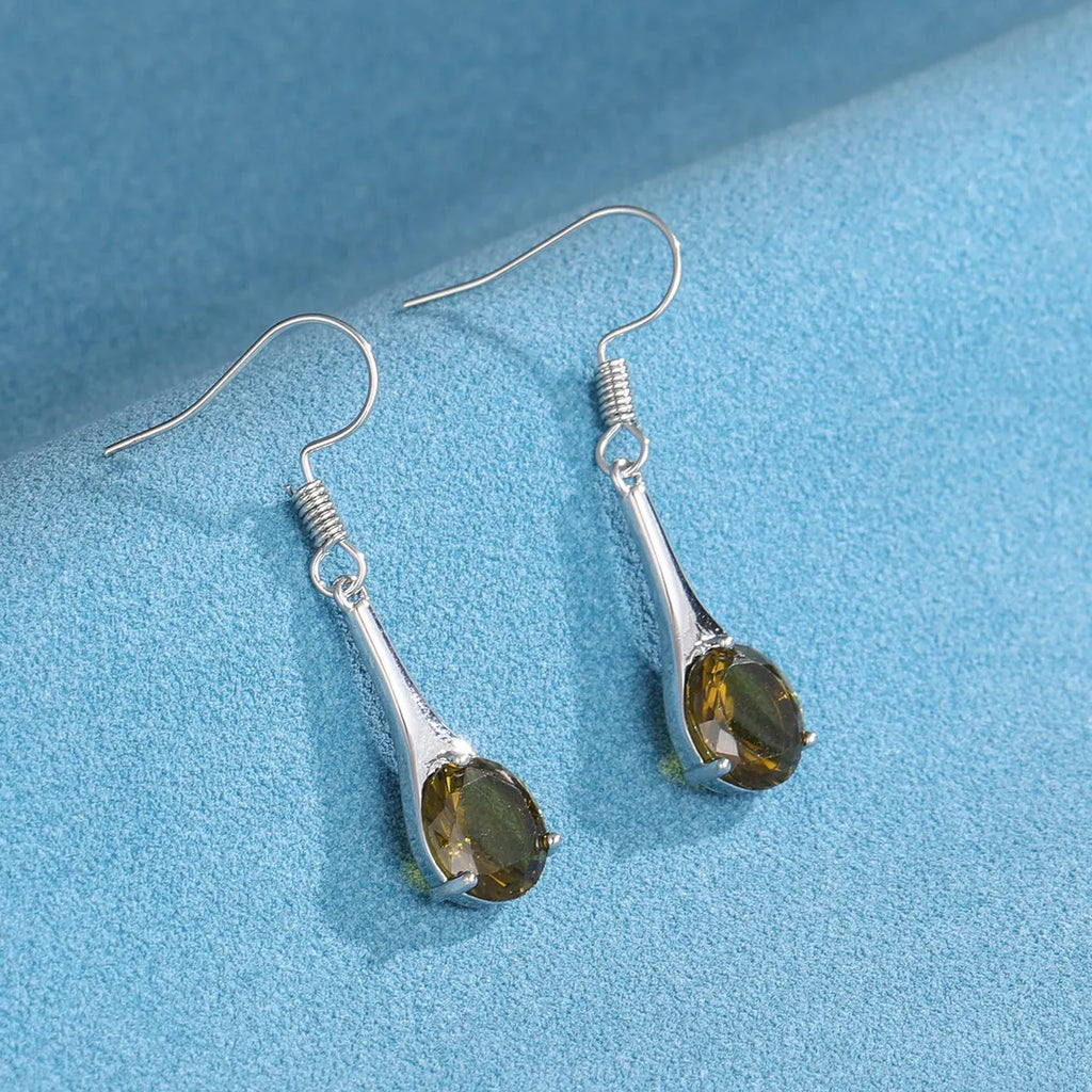 Olive green topaz coloured drop-shaped retro earrings for women on a plain background.