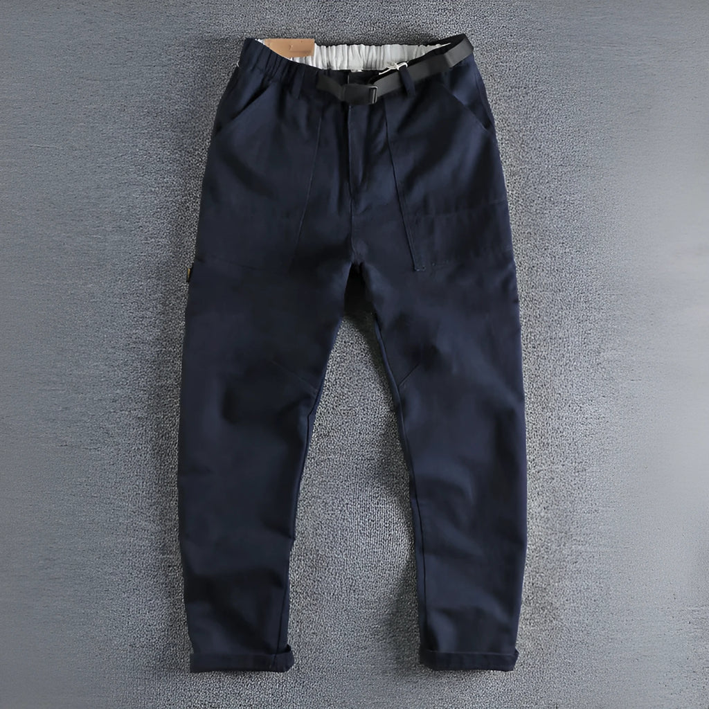 Men's khaki and dark blue cotton work trousers with mid waist and zipper fly on a size chart