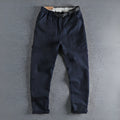 Men's khaki and dark blue cotton work trousers with mid waist and zipper fly on a size chart