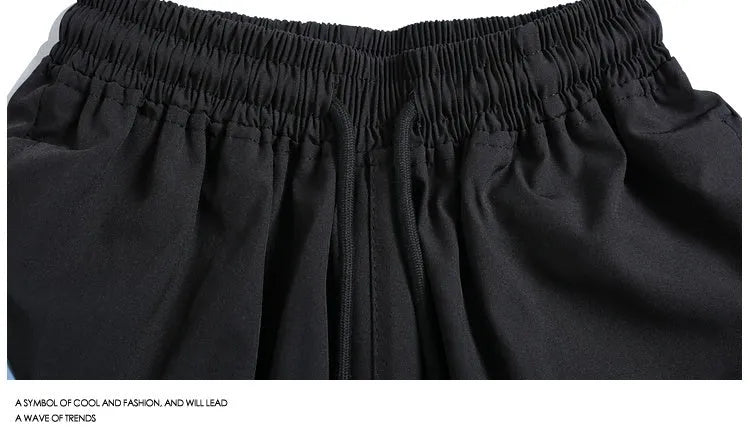 Men's black loose-fit quick-drying sports shorts with elastic waistband on a grey background