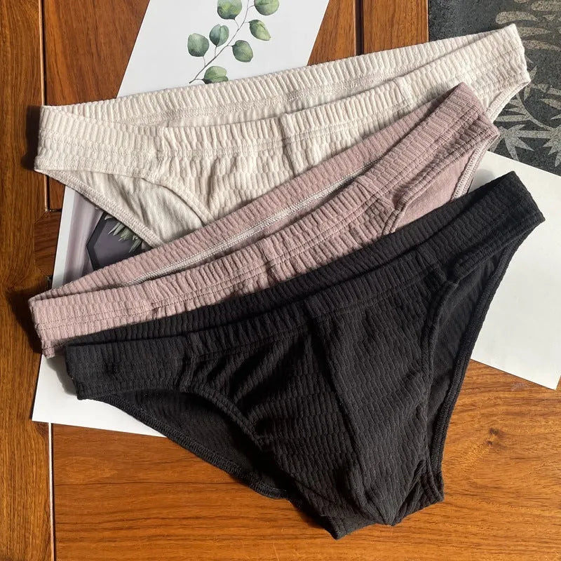 Men's solid colour cotton triangle briefs on a mid-waist, showing apricot, black, white and skin colour options.