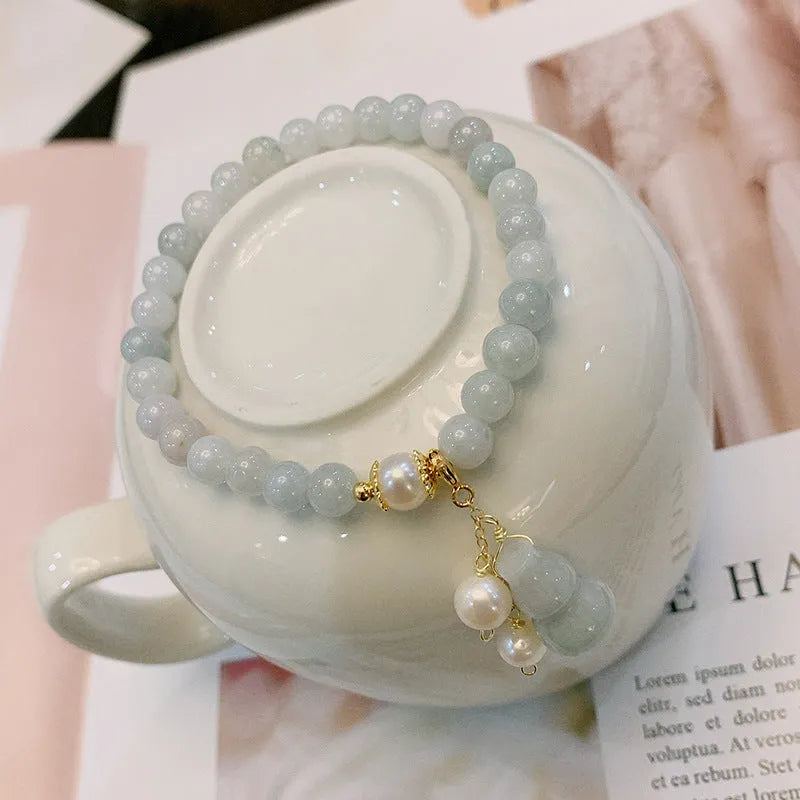 A handcrafted natural emerald jade bracelet with a detailed gourd charm, presented on a white background.