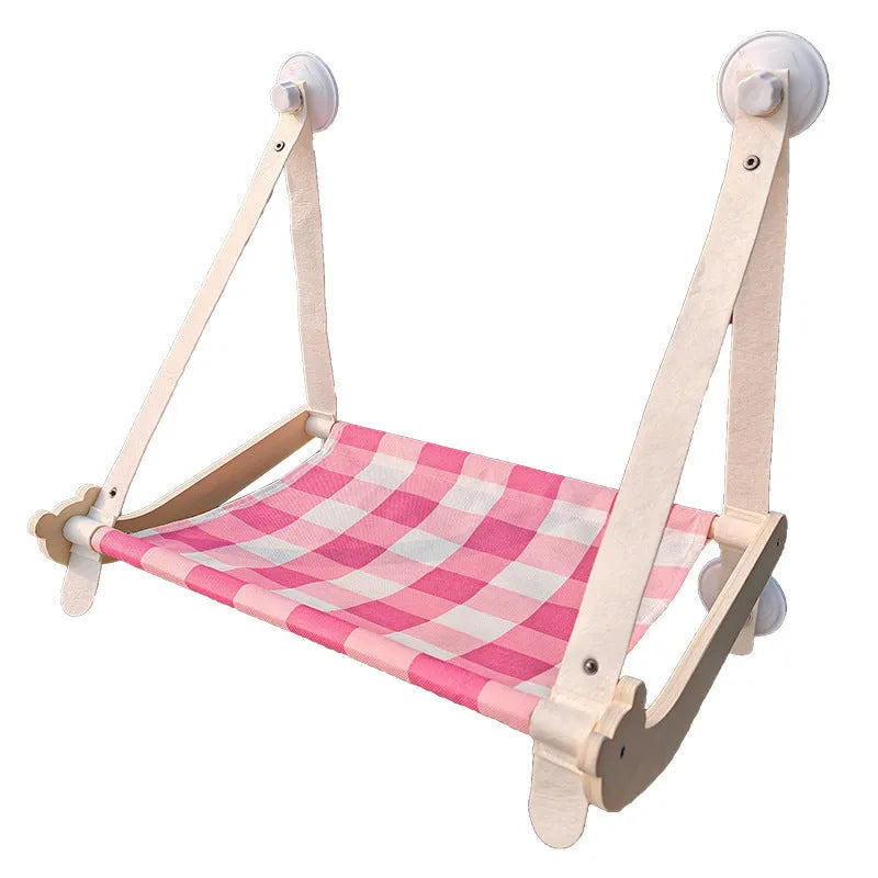 Foldable wooden cat window hammock with suction cups attached to a glass pane.