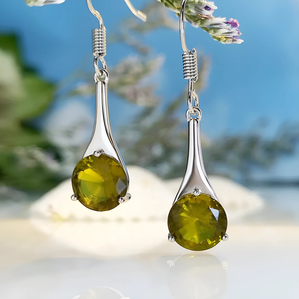Olive green topaz coloured drop-shaped retro earrings for women on a plain background.