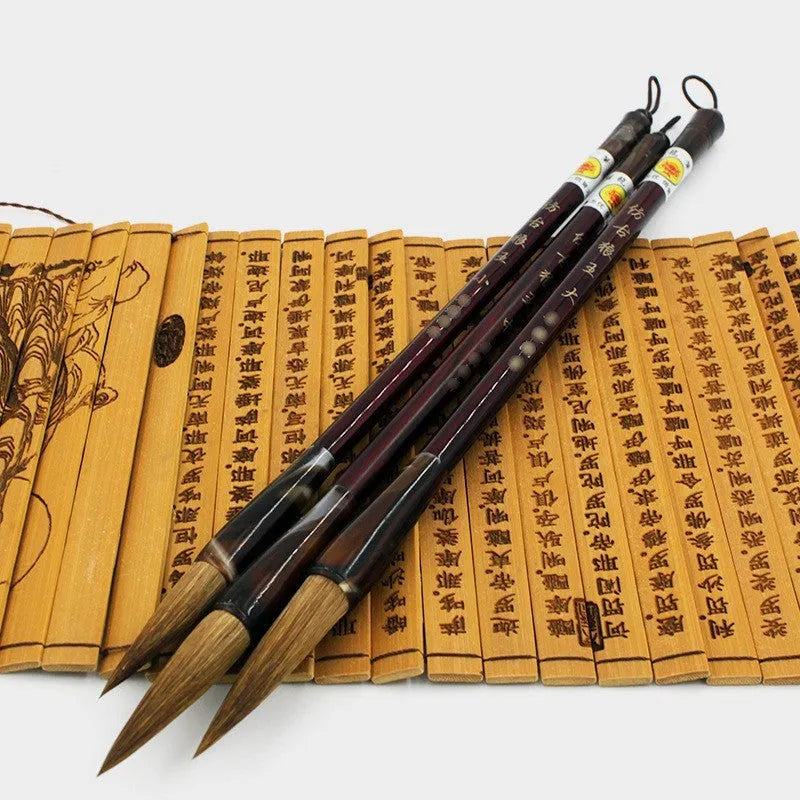 Set of three traditional Chinese calligraphy brushes with wolf hair bristles and steel ferrules in large, medium, and small sizes.