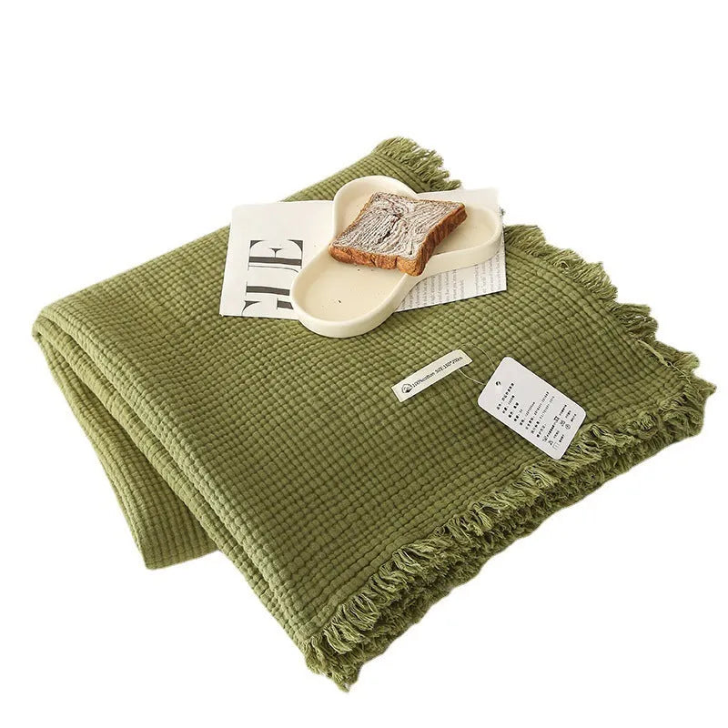 Four-layer gauze cotton blanket with tassel trim in navy blue colour laid flat.