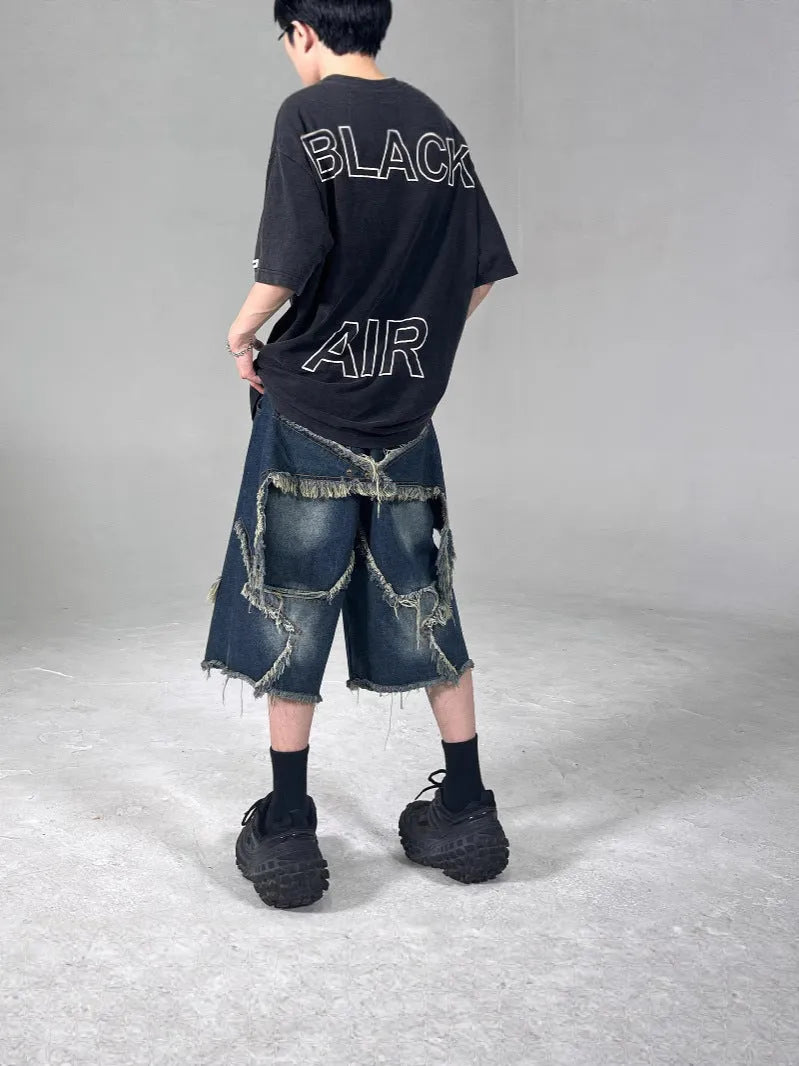 Blue denim shorts with a frayed five-pointed star detail on the leg, showing a loose, retro fit.