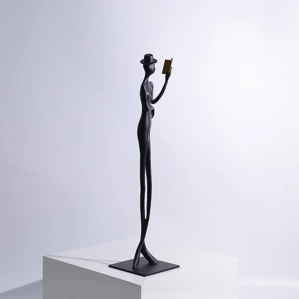 Black aluminium desktop sculpture of reading woman figure measuring 12x12x51cm