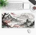 Large black gaming mouse pad with colourful anime character graphic on a desk with keyboard and mouse.