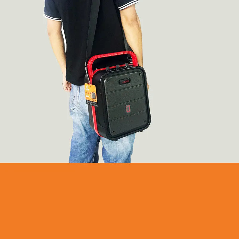 Portable black Bluetooth speaker with a wireless microphone, remote control, and carry strap.