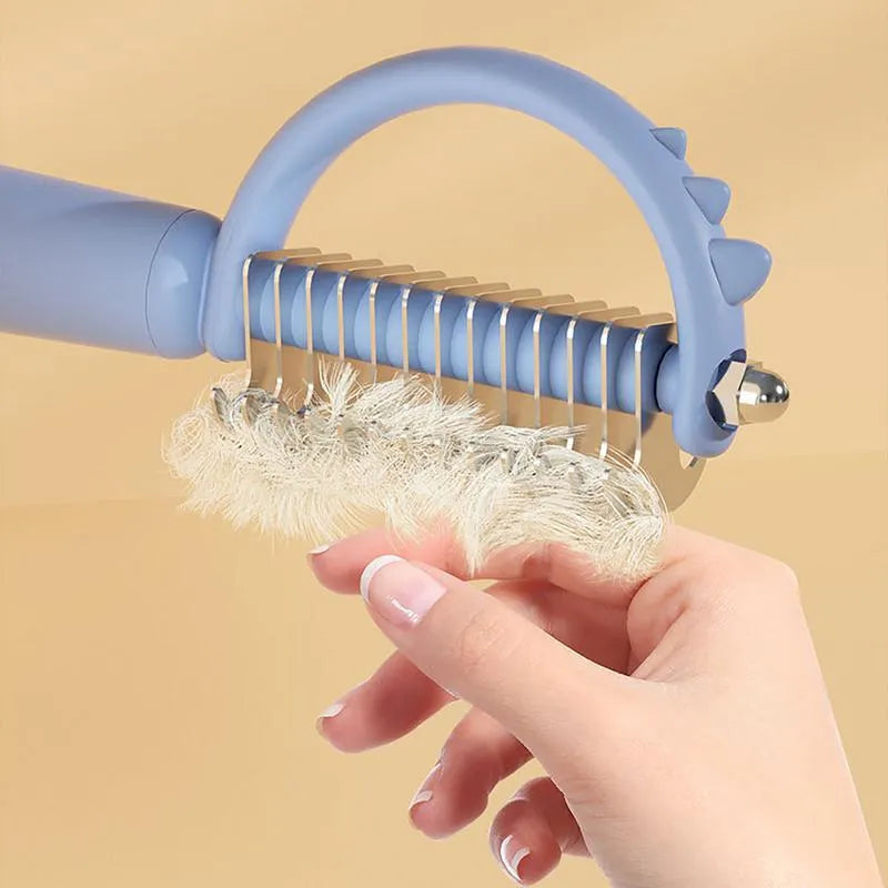 Dinosaur shaped cat brush with stainless steel bristles and self cleaning feature