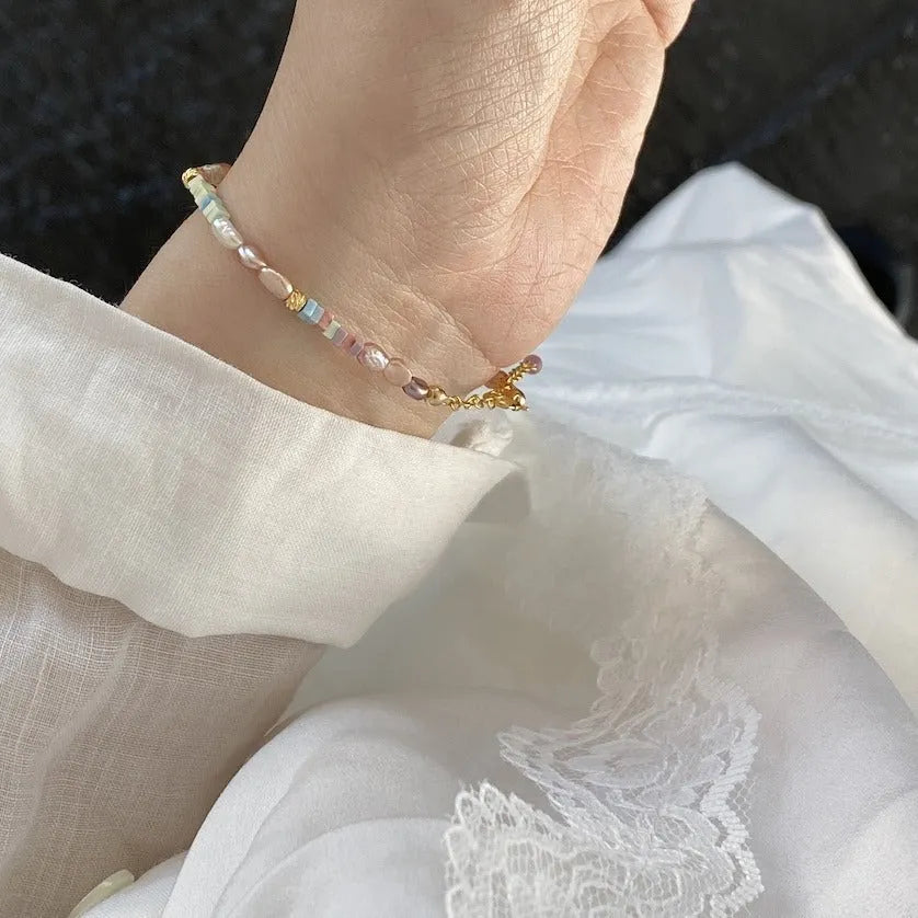 Close-up of a women's mini bracelet with irregular natural pearls set in 14K gilded purple silver, shown with its matching necklace.