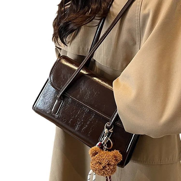 Brown women's PU leather crossbody shoulder bag with pendant, showing front view and adjustable double straps.