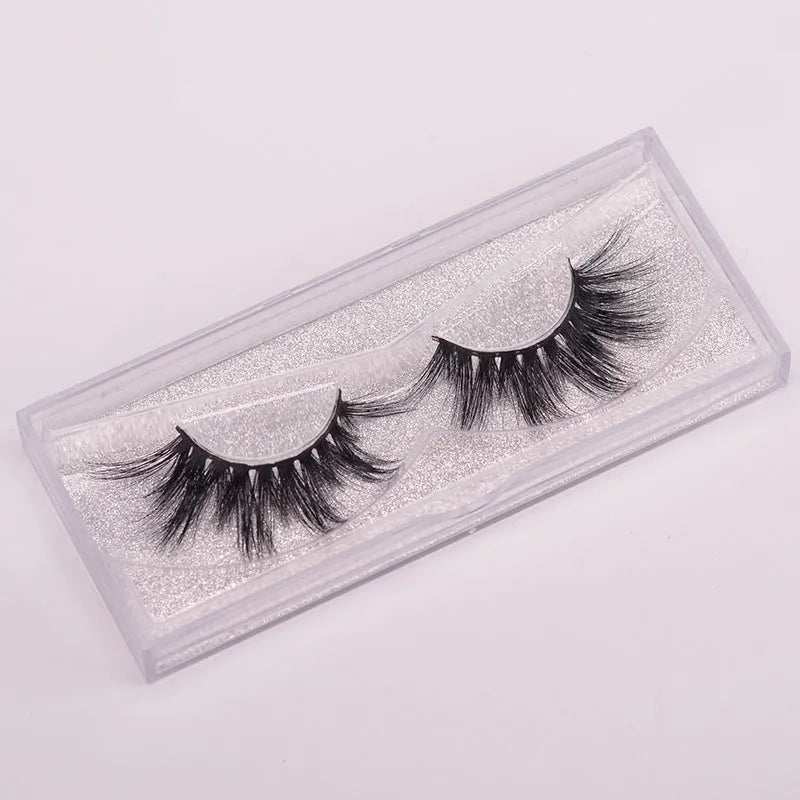 5D mink false eyelashes in natural black with curled ends, shown with double-headed glue brush and hair cap