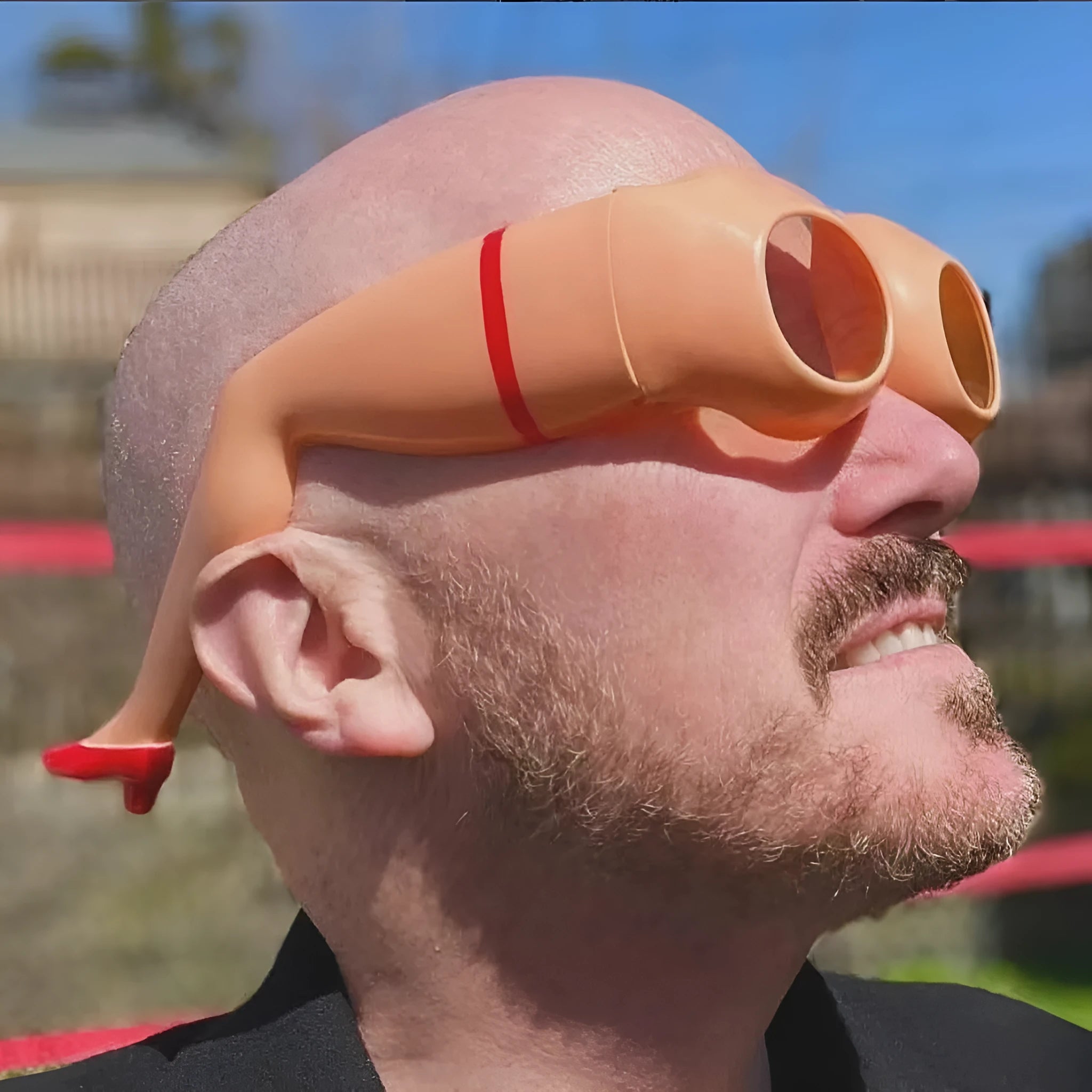 Orange plastic novelty sunglasses with oversized personality leg and hip design on the frame.