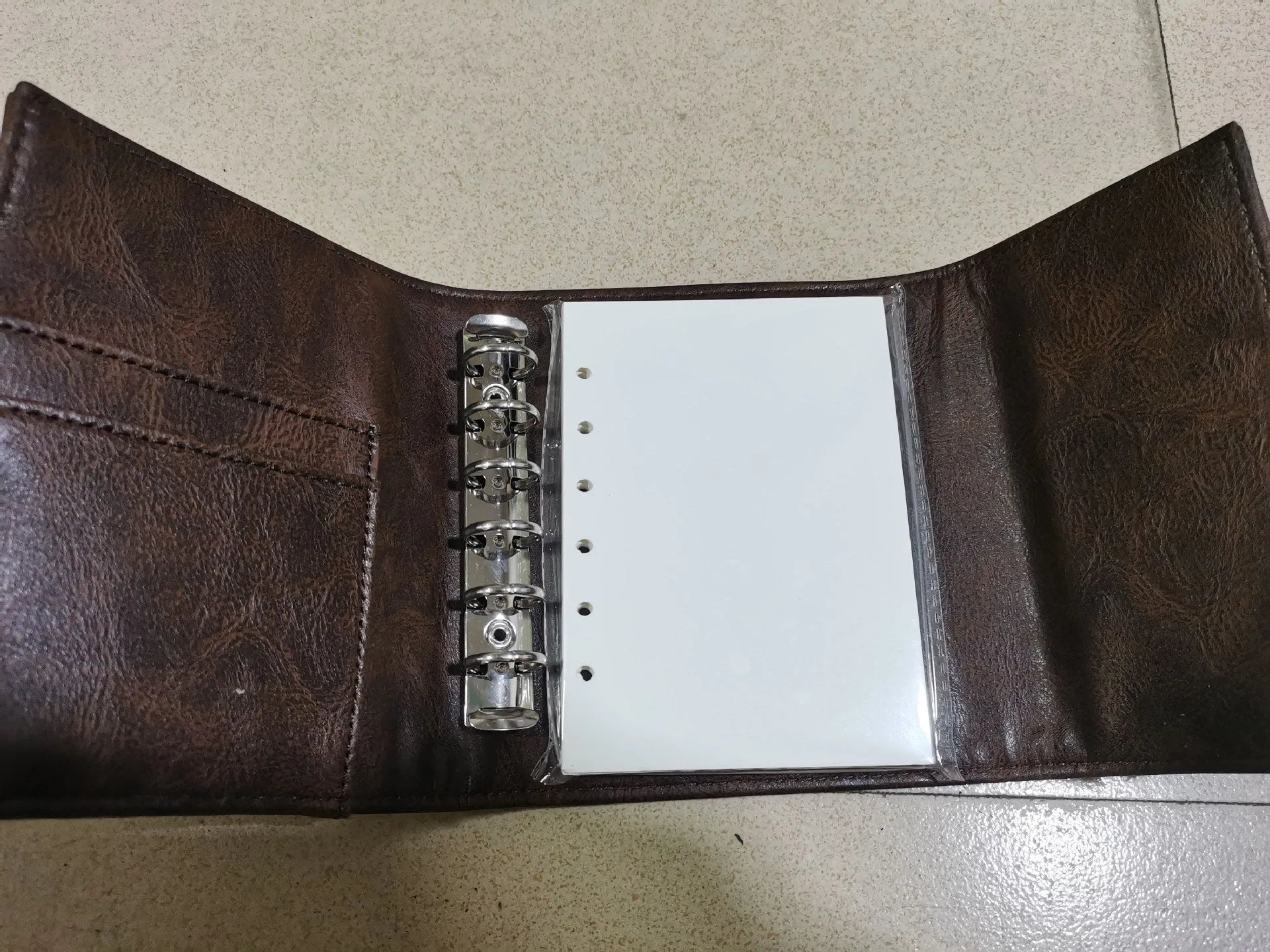 A7 brown PU leather-style notebook with loose-leaf binder binding, open to show 40g raw wood pulp paper