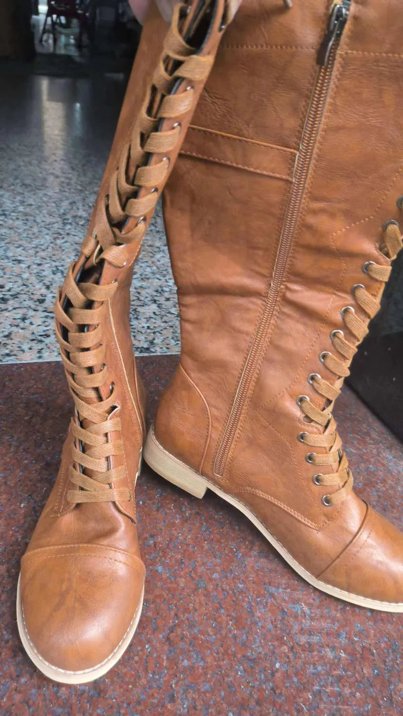 Women's black cross strap knight boots made from artificial PU, showing front strap detail.