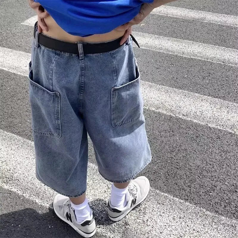 Man wearing blue high-waist straight-leg denim pirate shorts, showing cropped length and zipper fly
