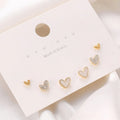 Three pairs of heart-shaped girly earrings in gold, black, black and white, and pink colours